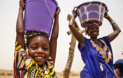 Aissata Sow (6) helps her grand-aunt Haby Moussa Sow (51) carry water back from the well. They are part of the USAID Yaajeende Project in Senegal Aissata