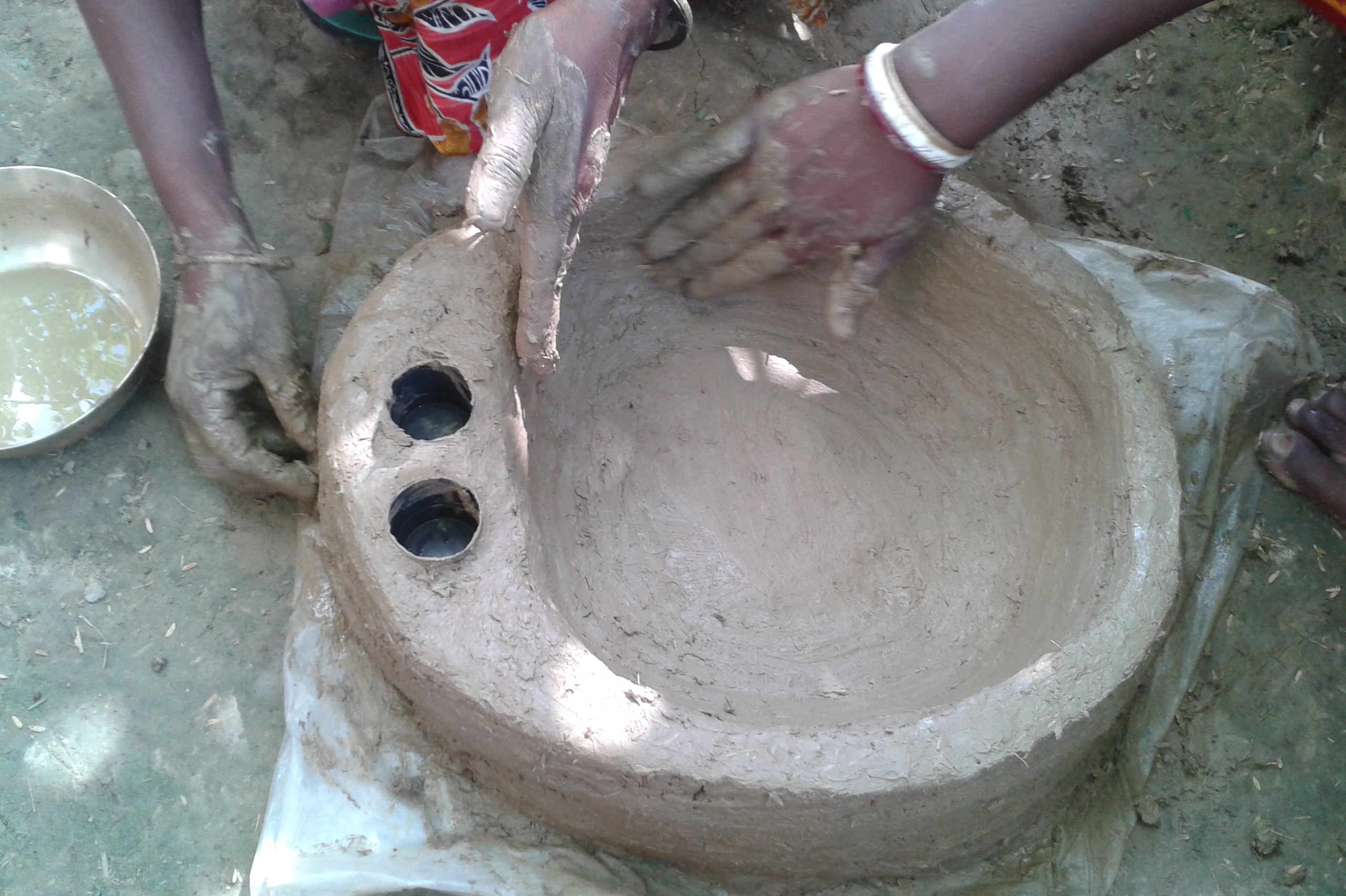 Sculpt the mixture into a round bowl shape, with two small holes on one side. Hands sculpting a hatching pot.