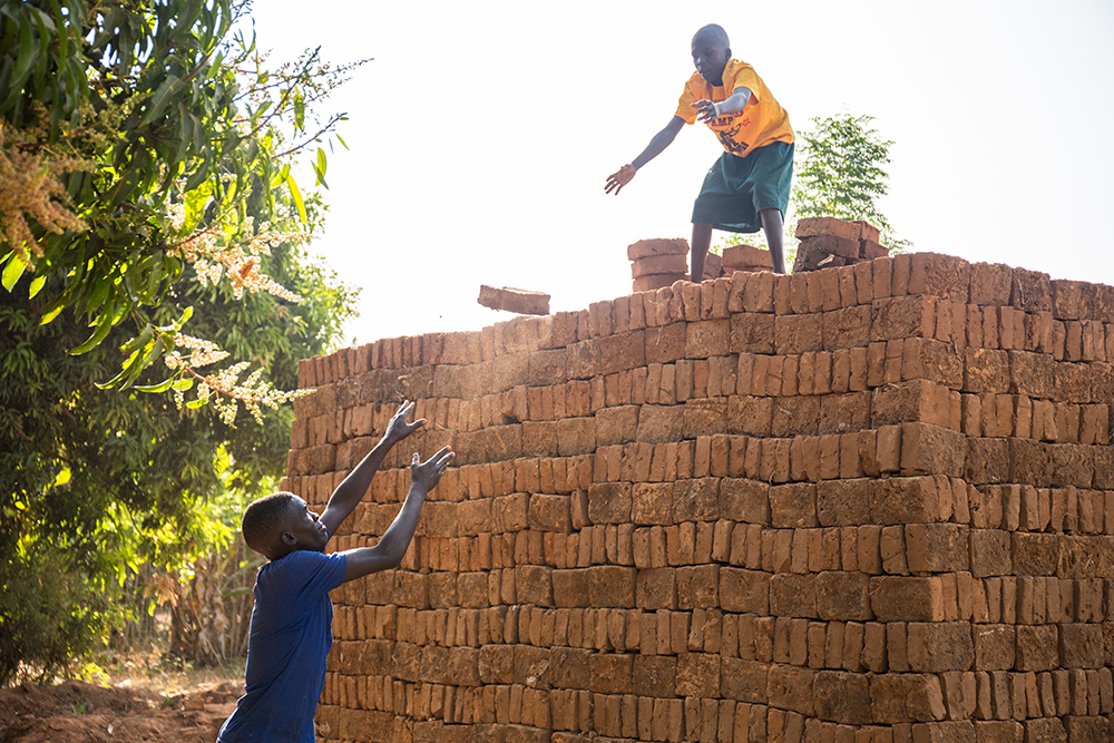 Ojok Ivan Emmanuel, 17, and his brother Ronnie Owekgiu, 12, work together to pile up clay bricks. Ojok Ivan Emmanuel, 17, and his brother Ronnie Owekgiu, 12, work together to pile up clay bricks.