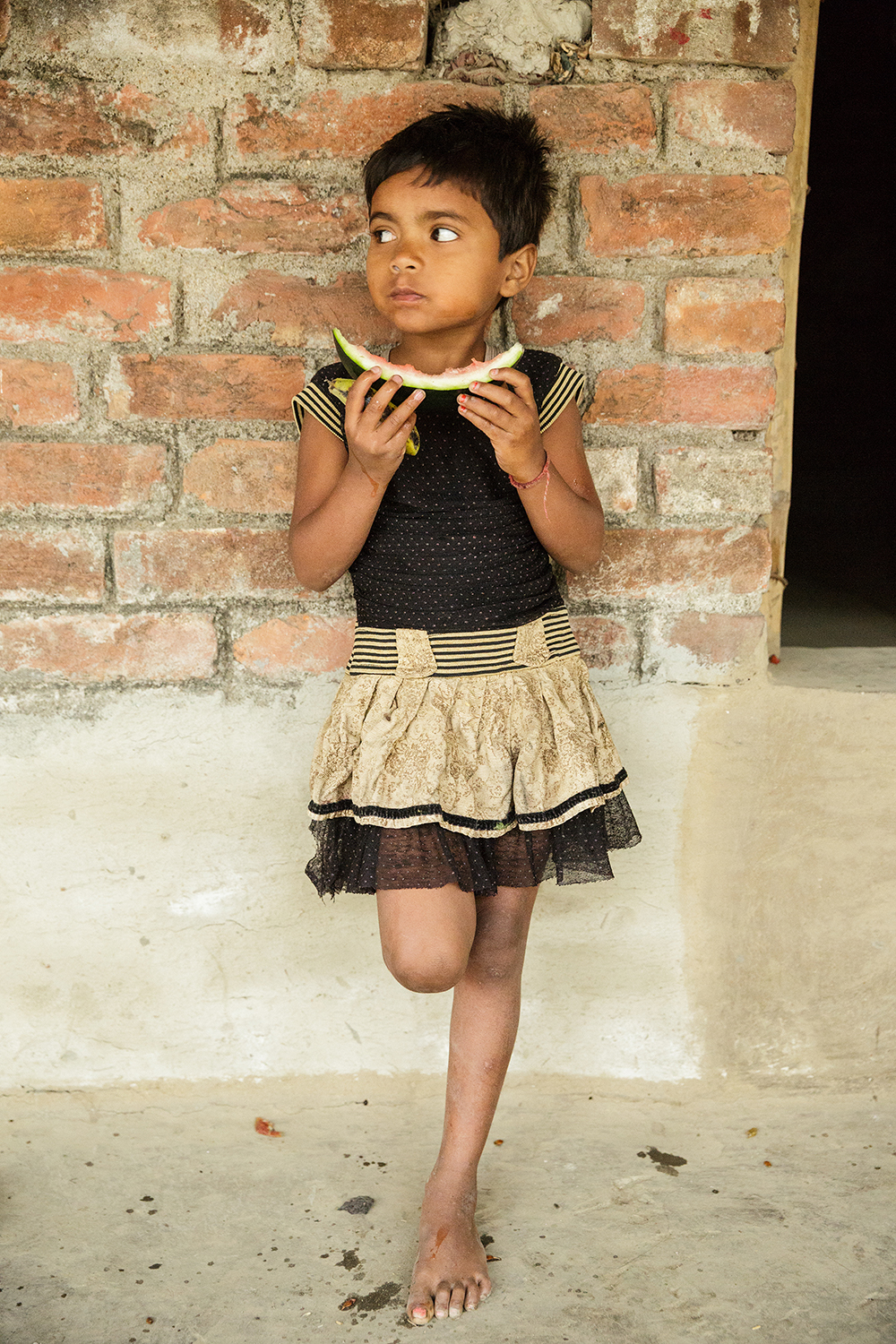 Aarti Nandan Kisku, 6, eats a slice of watermelon. Aarti's older siblings were stunted as children from malnutrition. Aarti's parents participated in nutrition education as part of a Heifer project, and Aarti is on track for her age. A young Indian girl eats a slice of watermelon.